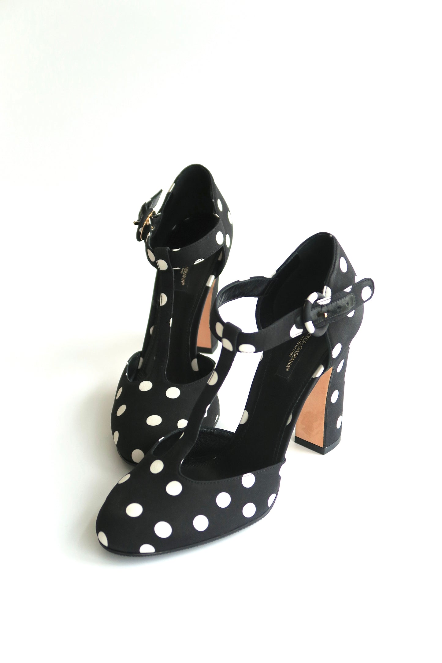 Black high-heeled shoes with white polka dots on a white background