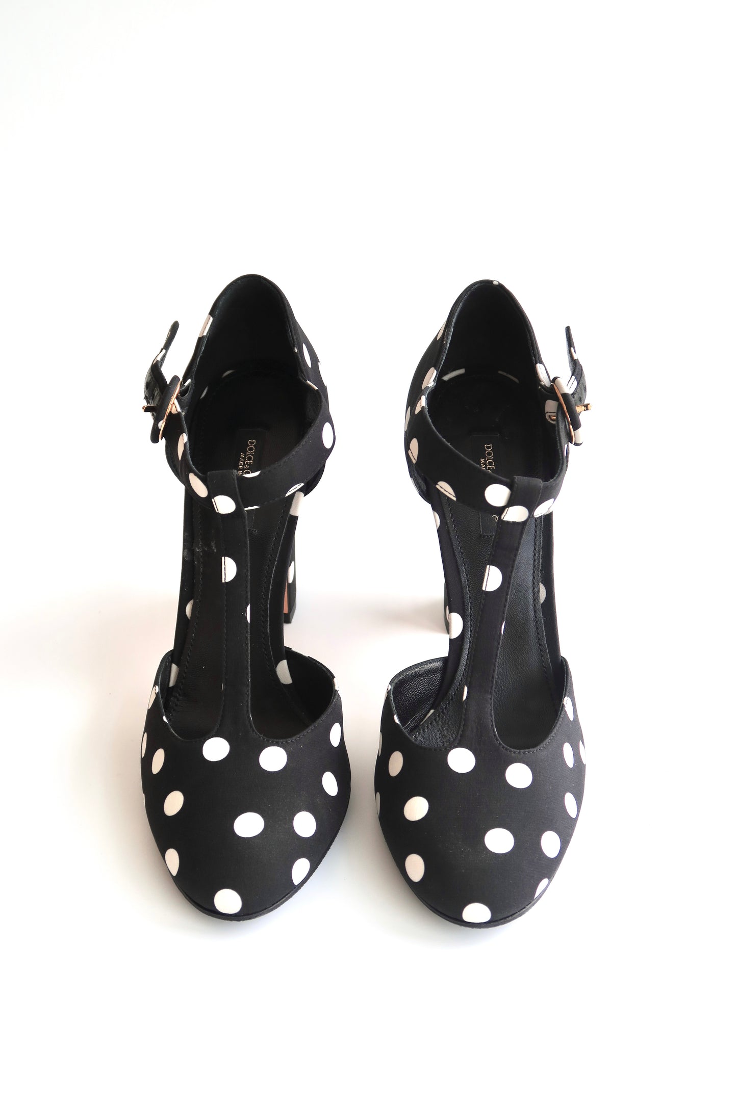 Black high-heeled shoes with white polka dots on a white background
