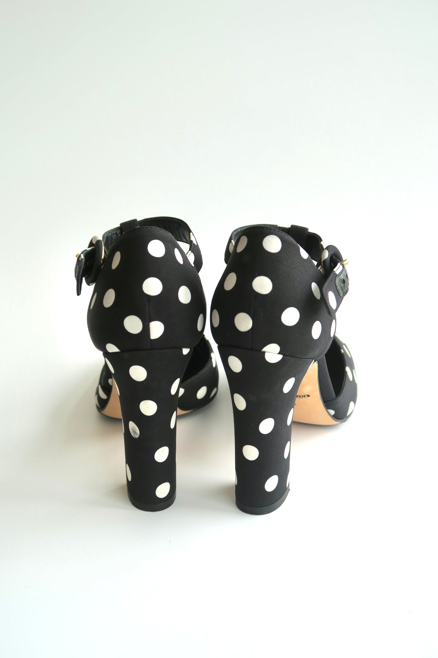 Black high-heeled shoes with white polka dots on a white background