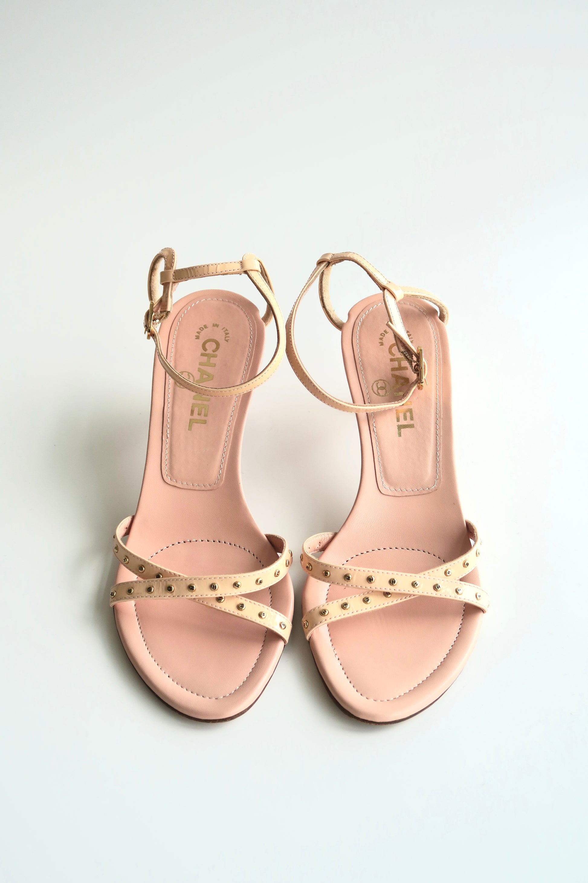Pair of pink sandals with gold accents on a light gray background