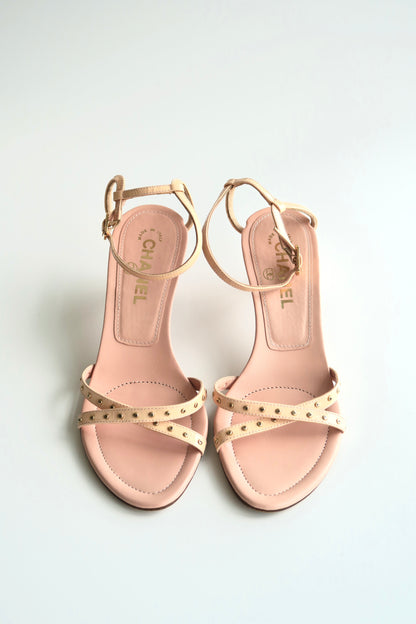 Pair of pink sandals with gold accents on a light gray background