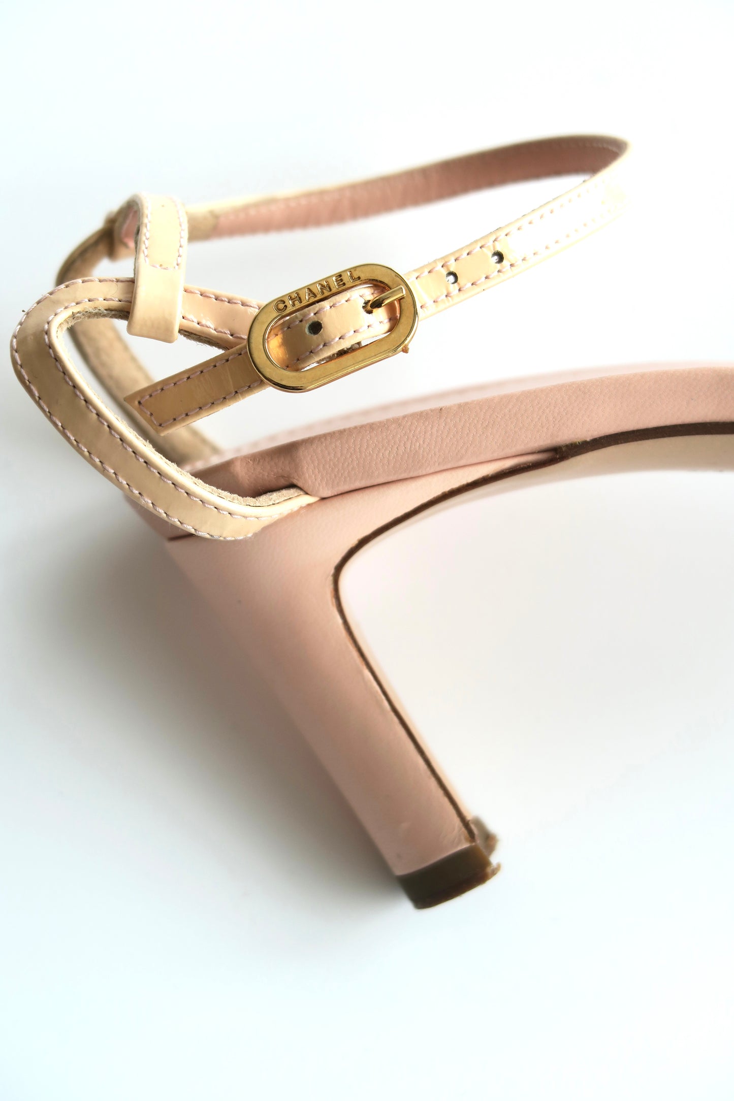Close-up of a rose gold high-heeled shoe with a strap on a white background