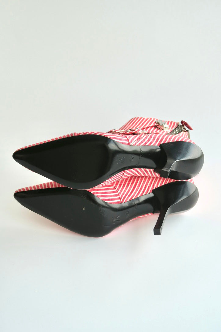 Black high-heeled shoes with red and white striped on a light gray background showing outsole condition