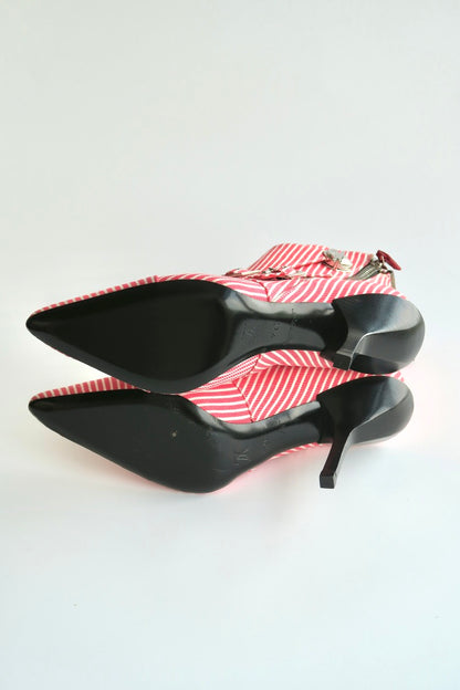 Black high-heeled shoes with red and white striped on a light gray background showing outsole condition